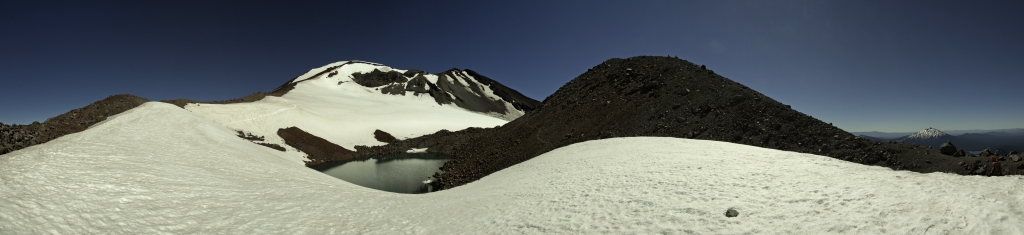 Panorama am kleinen Gletschersee des Lewis Glacier am Aufstieg auf die South Sister (3159m); der Aufstieg erfolgt von hier aus über die bröselige, aus grauer und rötlicher Lava und Schlacke bestehende Rippe links des Gletschers; im Panorama ganz rechts ist der Mt. Bachelor (2764m) zu sehen, Three Sisters Wilderness, Oregon