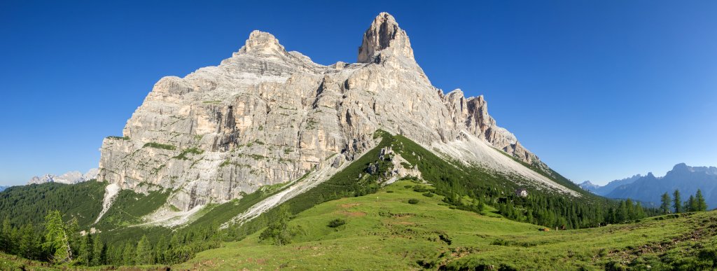 Das wuchtige Massiv des Pelmo (3168m) mit den beiden vorgelagerten Bastionen von Spalla Sud (3061m) und Spalla Est (3024m) erstrahlen im Licht der Morgensonne. Davor das Rifugio Venezia al Pelmo Alba Maria De Luca alias Pelmo-Hütte (1947m). Dolomiten, Juli 2013.