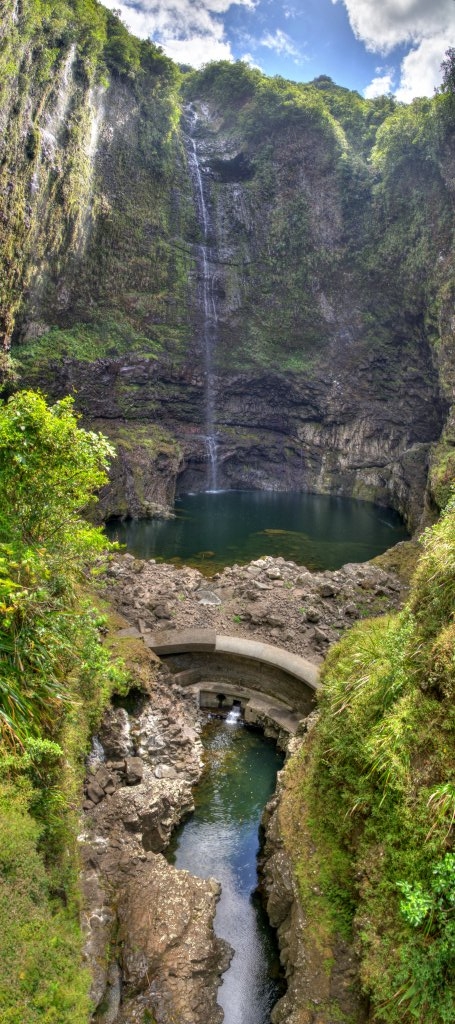 Hoher Wasserfall mit ausgeprägtem Pralltopf und einer Vorsperre des Wasserkraftwerksbetreibers EDF im Tal von Takamaka auf dem Weg vom Endpunkt der Strasse zur Stauanlage Takamaka I. Das Vertikalpanorama wurde von einer hohen Hängebrücke über dem Ablauf der kleinen Vorsperre aufgenommen. Da am frühen Morgen noch krasses Gegenlicht herrschte, wäre hier ohne die HDRI-Technik von dem Wasserfall und seinem kleinen See im Schatten nicht viel zu sehen gewesen. La Reunion, Oktober 2013.