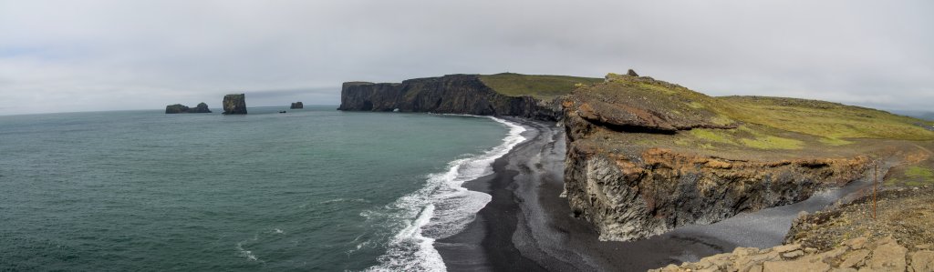 Blick auf die durchlöcherte Basaltküste und den schwarzen Basalt-Sandstrand von Dyrholaey, Island, Juli 2015.