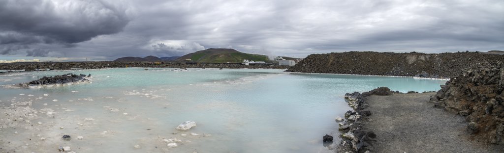 Dramatische Wolkenstimmung über der Blauen Lagune. Das Svartsengi Geothermal-Kraftwerk leitet das immer noch heisse Abwasser in künstlich angelegte Teiche. Die Geothermalquelle hier bei Grindavik ist eine Anomalie, da salzhaltiges Meerwasser von der Küste im tiefen Untergrund in das Lavafeld einsickert, von der oberflächennahen Erdwärme erwärmt wird und das Meeressalz Minerale aus der Lava heraus löst und mit nach oben befördert. Zum einen verhindert das die Rückverpressung des Geothermalwassers, zum anderen verdankt die Blaue Lagune diesen Mineralien ihre türkis-blaue Farbe, Island, Juli 2015.