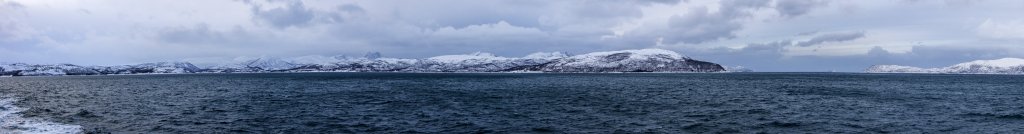 Die M/S Trollfjord auf der Durchfahrt im Gisundet zwischen der Insel Senja und dem norwegischen Festland mit Blick auf die Bergketten Vardan, Kårvikkjølen und Vassbruna, Norwegen, Februar 2015.