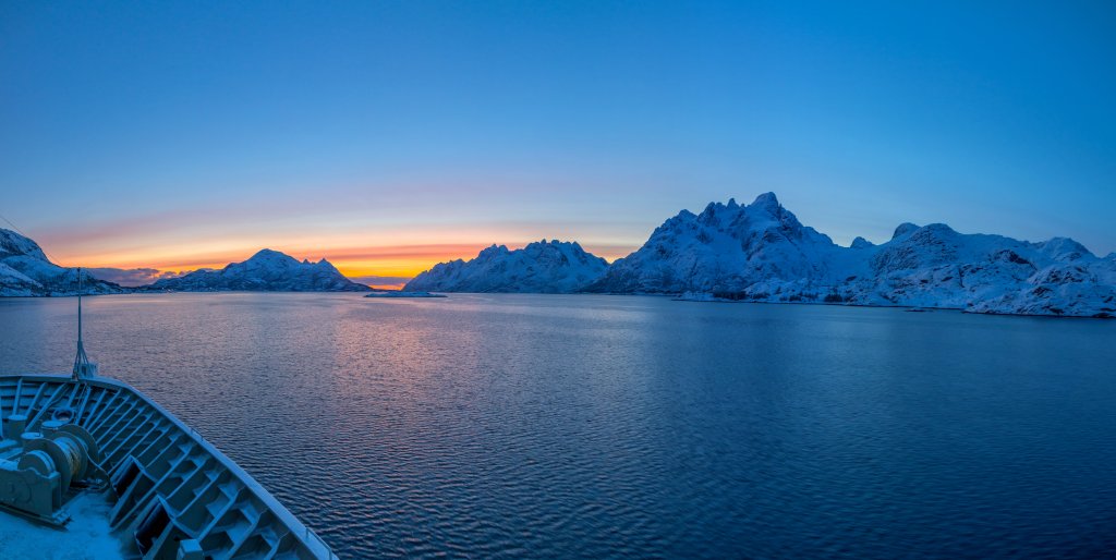 Die M/S Trollfjord bei Sonnenuntergang in der Passage des Raftsundet mit Kurs auf Svolvær und mit Blick auf Grønåsen (629m), Langstrandtindan (934m), Rørhoptindan (829m) und Trolltindan (1036m), Norwegen, Februar 2015.