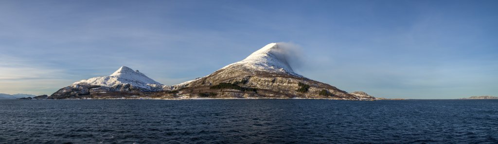 Der stürmische Wind bläst über die Gipfel des Breitinden (818m) und des Breitomma (803m) auf der Insel Tomma bei Nesna, Norwegen, Februar 2015.