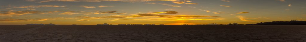 Sonnenunergang im Salar de Uyuni - die Strahlen der untergehenden Sonne werfen den Schatten der weit entfernten Berge an den Wolkenhimmel, Bolivien, November 2016.