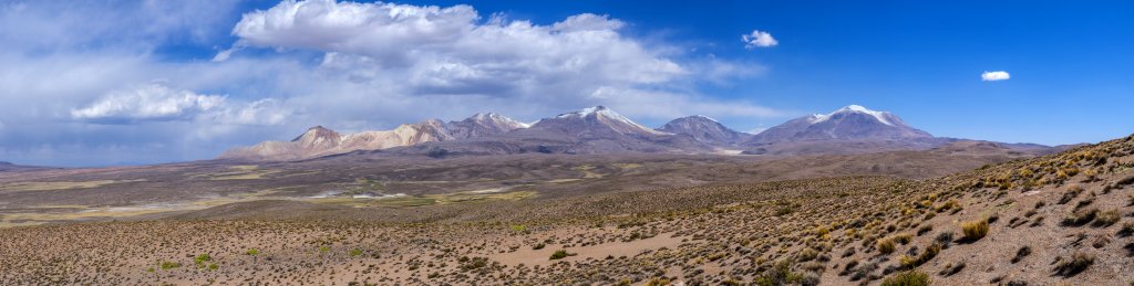 Panorama der Vulkankette an der chilenisch-bolivianischen Grenze mit Uqi Uquini (5532m), der Quimsachata Vulkangruppe mit dem Cerro Umurata (5601m), dem Volcan Acotango (6052m) und dem Volcan Capurata (6039m), sowie ganz rechts dem Volcan Guallatiri (6071m), Chile, November 2016.