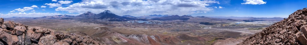 Gipfel-Panorama auf dem Cerro Guane-Guane (5097m) mit Blick auf die beiden Vulkane Pomerape (6282m) und Parinacota (6348m), die Lague Cotacotani und der Lago Chungara sowie die fern im Süden gelegenen Vulkane Umarata (6071m), Acotango (6052m), Cerro Elena Capurata (5990m) und Guallatiri (6071m). Tief unter uns an der Strasse liegt der kleine Ort Parinacota., Chile, November 2016.