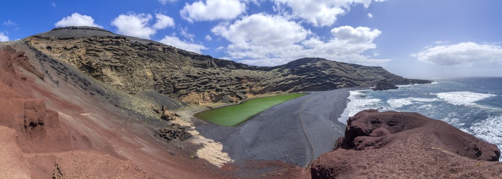 Die grüne Lagune am Strand von El Golfo bildet einen fantastischen Kontrast mit den roten Vulkanfelsen und den vom Atlantikwind erodierten Vulkanascheablagerungen, Lanzarote, Kanarische Inseln, März 2017.