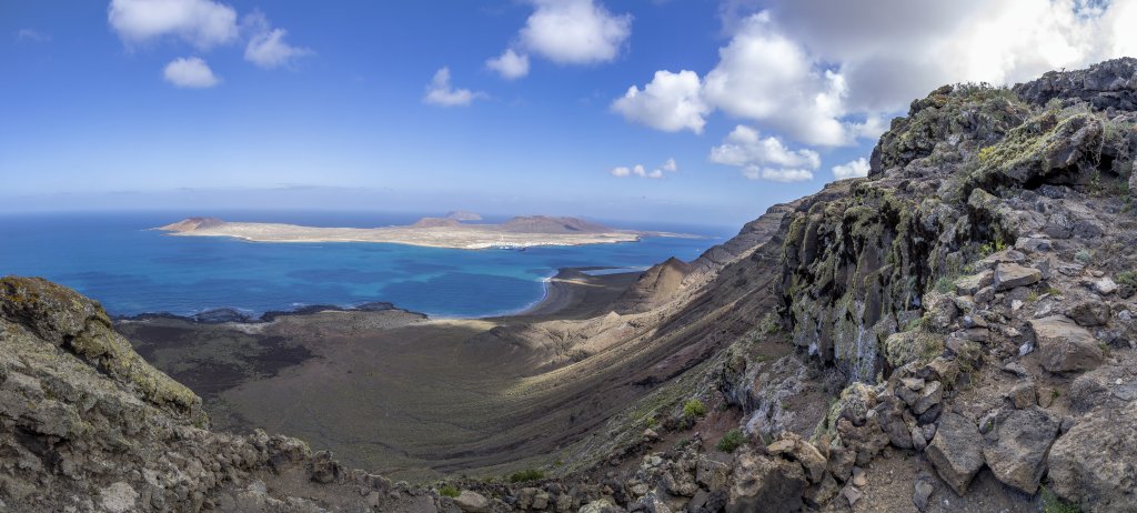 Abstieg auf dem Camino de Guatifay von den Felsencliffs El Risco de Famara hinunter zum Playa del Risco gegenüber der vorgelagerten Insel La Graciosa, Lanzarote, Kanarische Inseln, März 2017.