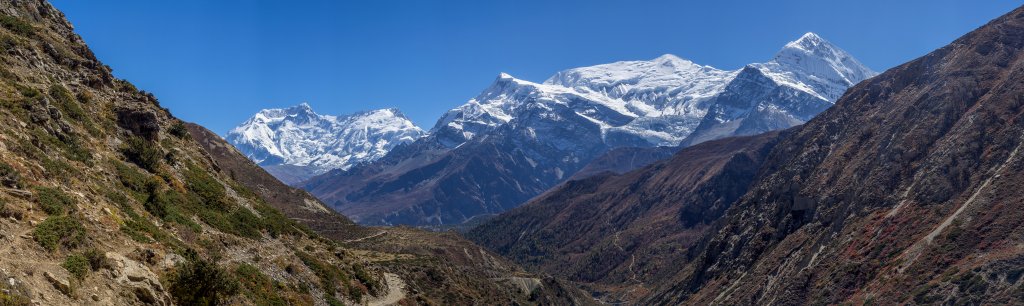 Kurz vor Erreichen von Yak Kharta ein Blick zurück auf das Dreigestirn aus Annapurna II, Annapurna III und Gangapurna; auf der rechten Talseite führt der Weg hinüber zum Paßübergang am Tilicho Lake, Nepal, Oktober 2017.