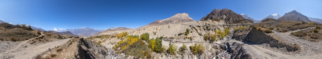 Beim Verlassen von Muktinath eröffnet sich ein Blick zurück auf den Einschnitt des gestern überquerten Thorong La (5416m) zwischen Yakawa Kang (6482m) und Thorong Peak (6144m). Im Westen blickt man auf Tilicho Peak (7134m), Nilgiri (7061m), den Dhaulagiri (8167m), Tukuche Peak (6920m) und den Sangdachhe Himal (6403m), Nepal, Oktober 2017.