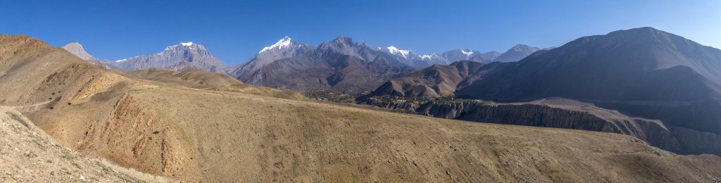 Blick zurück auf die Ortschaften Muktinath, Jarkot und Khinghar unterhalb des Passes des Thorong La (5416m) zwischen Yakawa Kang (6482m) und Thorong Peak (6144m), gefolgt von Khatung Kang (6484m), Tilicho Peak (7134m) und Nilgiri (7061m), Nepal, Oktober 2017.