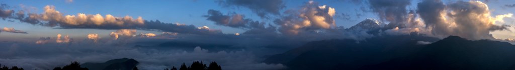 Ziemlich wolkiger Sonnenaufgang auf dem Poon Hill (3210m) über Ghorepani (2863m). Von rechts nach links sieht man zwischen den Wolken den Gipfel der Annapurna I (8091m), des Tukuche Peak (7134m), des Dhaulagiri (8167m), Dhaulagiri V (7618m), Dhaulagiri IV (7661m) und die Spitze des Gurja Himals (7193m), während sich der dazwischen gelegene Bergkamm mit Dhaulagiri II (7751m) und Dhaulagiri III (7715m) ebenfalls in der Wolke verbirgt. Rechts von Annapurna I sieht man durch die Wolken noch Fragmente der Basis der Annapurna South (7219m), Nepal, Oktober 2017.