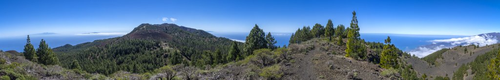 Blick vom Montana la Barquite (1809m) über die Vulkan-Route nach Süden zum Pico Nambroque (1922m) und zum Crater del Hoyo Negro (1886). Auf der linken Seite ist Teneriffa mit dem verschneiten Teide (3718m) sowie La Gomera zu erkennen, während auf der rechten Seite El Hiero am Horizont zu sehen ist., La Palma, Kanarische Inseln, Februar/März 2018.