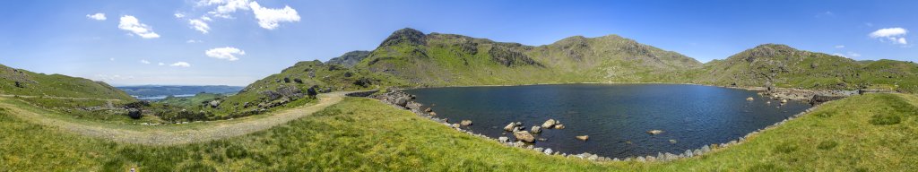 360-Grad-Panorama. Am Ufer von Levers Water unterhalb von The Old Man of Coniston (802m), Brim Fell, Levers Hawse, Swirl How (801m) und Wetherlam (762m) und einem Ausblick auf den See Coniston Water, Lake District, Großbritannien, Juni 2018.