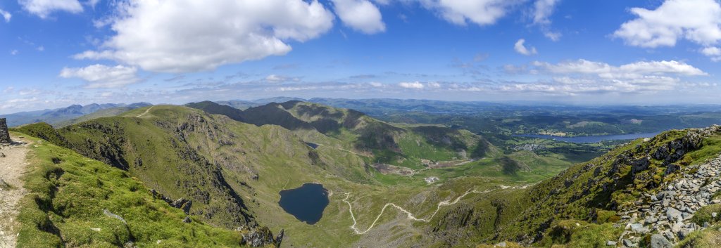 Am Gipfel des Old Man of Coniston (803m) mit Blick auf den Brim Fell (796m), Swirl Howe (802m), Wetherlam (763m), Levers Water, Low Water und den Coniston Lake. Links im Hintergrund die Berggruppe der Wainwrights mit dem Sca Fell (964m) und Scafell Pike (978m) - die höchsten Berge Englands, Lake District, Großbritannien, Juni 2018.