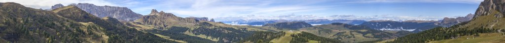 Auf Höhe der Murmeltierhütte (2131m) eröffnet sich am Fusse des Plattkofel ein weites Panorama über Teile des Rosengartens, die Gruppe der Rosszähne, das Schlernmassiv, die ferne Ortlergruppe, Teile des Alpenhauptkamms, den Innerraschötz-Kamm sowie die Seceda und Fermeda, Seiseralm, Südtirol, Oktober 2019.