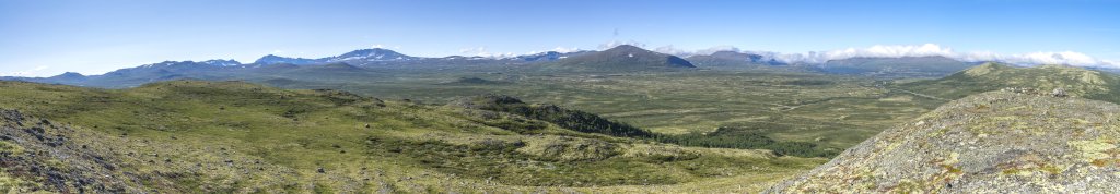 Weiter Blick über das Dovrefjell vom Tverrfjellgruver (1221m) mit den Gipfeln des Hatten (1731m), des Svanatindan (2209m), der Snohetta (2286m) und des Kolla (1651m) sowie dem Gebiet von Knutshoe (1517m), Hjerskavlen (1293m), Hjerkinnshoe (1288m) und Hjerkinnskollan (1259m) auf der anderen Seite der E6/Trondheimsvegen, Norwegen, Juli 2022.