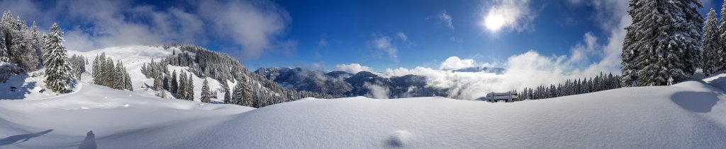Panorama auf dem Weg zur Tristmahlnschneid (1452m) unterhalb der Tristmahlnalm mit Blick auf den Gipfel der Tristmahlnschneid, auf Geigelstein und Breitenstein im Osten sowie die Gebirgsketten von Zahmem und Wildem Kaiser im Süden, Chiemgauer Alpen, Januar 2015.