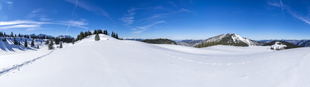 Friedliche Winterlandschaft an der Moosenalm unterhalb des Schafreuter. In der Ferne grüßen die hohen Karwendelberge von Östlicher Karwendelspitze (2537m) und Vogelkarspitze (2522m), rechts davon der Vorderskopf (1858m), das Estergebirge mit dem Krottenkopf (2086m), der Simetsberg (1836m), der Jochberg (1565m) sowie in der Nachbarschaft das Stuhlbachjoch (1737m) und Grasköpfl (1753m) und das Brandeck (1492m), Karwendel, Februar 2019.