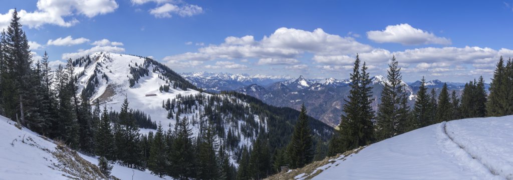 Blick vom Wallberg kurz unterhalb des Wallberg-Kapellchens auf den benachbarten Setzberg (1708m), das noch tief verschneite Karwendel, den Leonhardstein, Sonnberg, Buchstein, Hochplatte, Seekarkreuz und Hirschberg, Mangfallgebirge, Bayrische Alpen, April 2021.