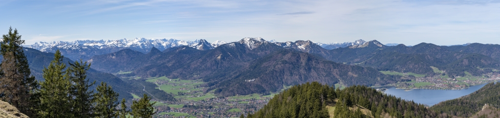 Großes Alpen-Panorama vom Gipfel der Baumgartenschneid (1448m) über dem Tegernsee und Rottach Egern mit weitem Blick über Karwendel, Wettersteingebirge, Soiernspitze bis hin zur Zugspitze. In der ersten Reihe stehen der Leonhardstein, Roß- und Buchstein, Hirschberg, Spitz-, Auer- und Ochsenkampel sowie der Fockenstein mit der Aueralm, Mangfallgebirge, Bayrische Alpen, April 2024.